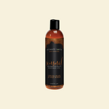 Bottle of Intimate Earth massage oil on a beige background
