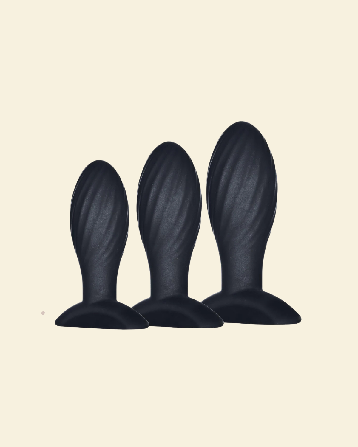 Three black silicone butt plugs of different sizes on a beige background