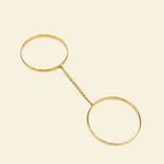 Gold bracelet with two circular ends on a beige background