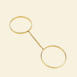 Gold bracelet with two circular ends on a beige background