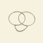 Two silver hoop earrings on a beige background