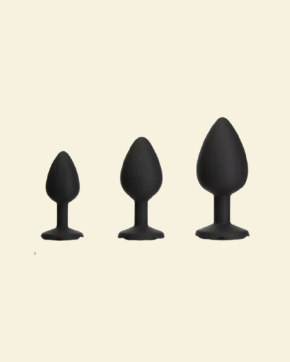 Three black silicone butt plugs of different sizes on a beige background