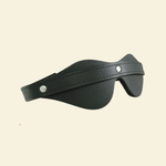 Black leather blindfold on beige background