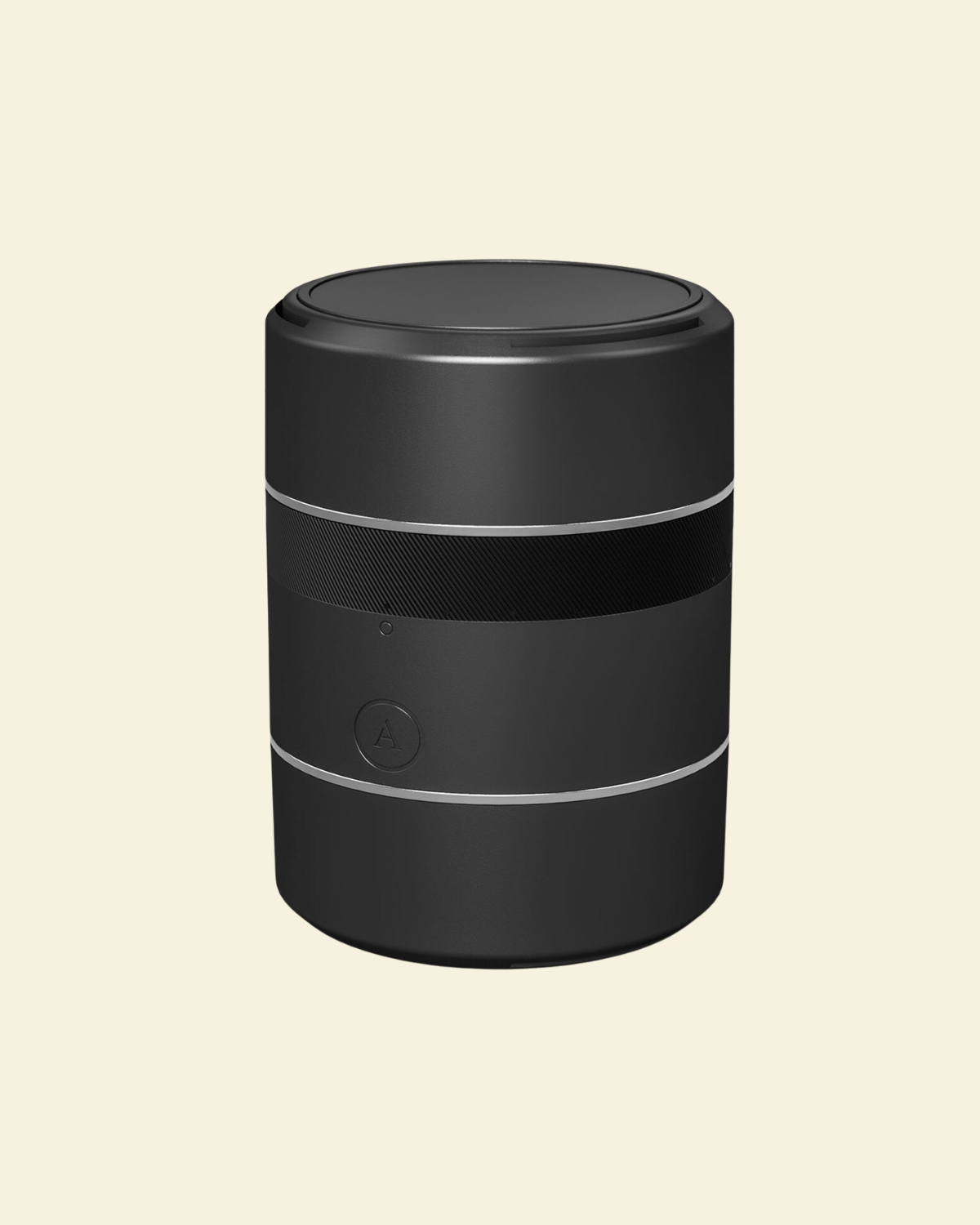 A black cylindrical portable stroker with a textured middle band and thin silver accent rings, shown on a solid light cream background.