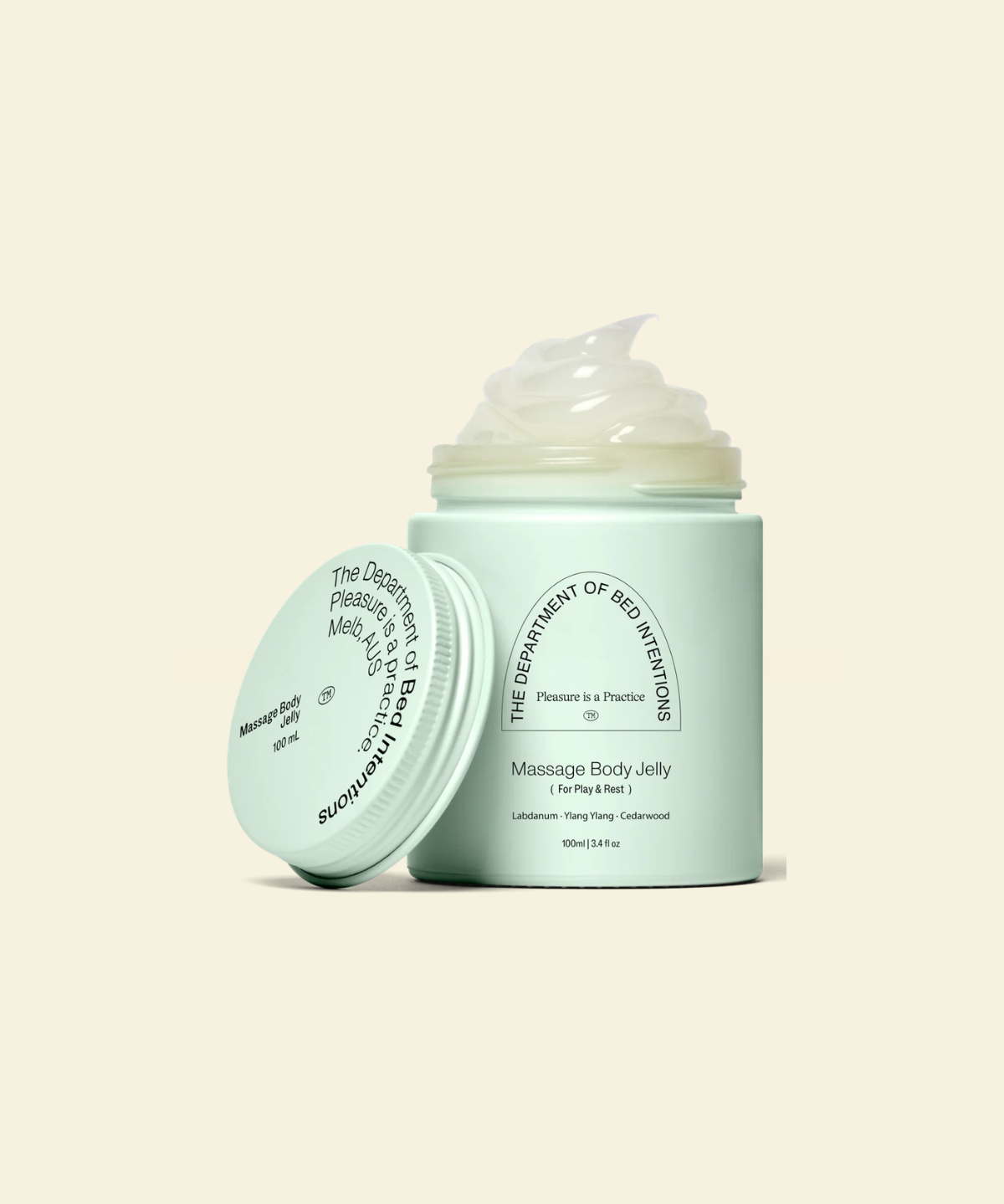A mint green jar of massage body jelly with its lid leaning against it, showing a dollop of pale yellowish-green jelly on top. The text on the jar reads 'The Department of Sex Education' and 'Massage Body Jelly'.