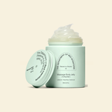 A mint green jar of massage body jelly with its lid leaning against it, showing a dollop of pale yellowish-green jelly on top. The text on the jar reads 'The Department of Sex Education' and 'Massage Body Jelly'.