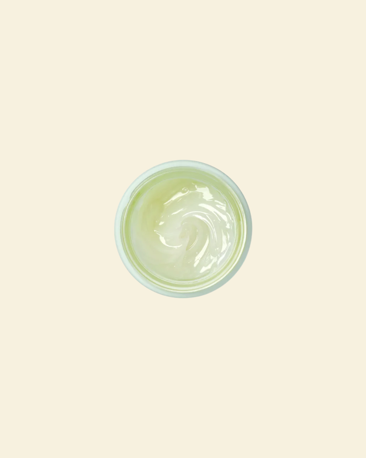 A top-down view of a small round container filled with a pale yellow-green cream or gel, centered on a solid light beige background.