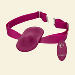 A magenta pink wearable vibrator with an adjustable strap and a matching oval-shaped remote control, displayed on a solid cream background.