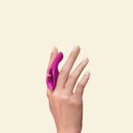 Hand holding a magenta finger vibrator between fingers