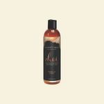 Bottle of Intimate Earth Chai Fragrance Massage Oil on a beige background