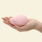 A hand holding a soft pink palm vibrator by Tenga Iroha