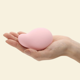 A hand holding a soft pink palm vibrator by Tenga Iroha