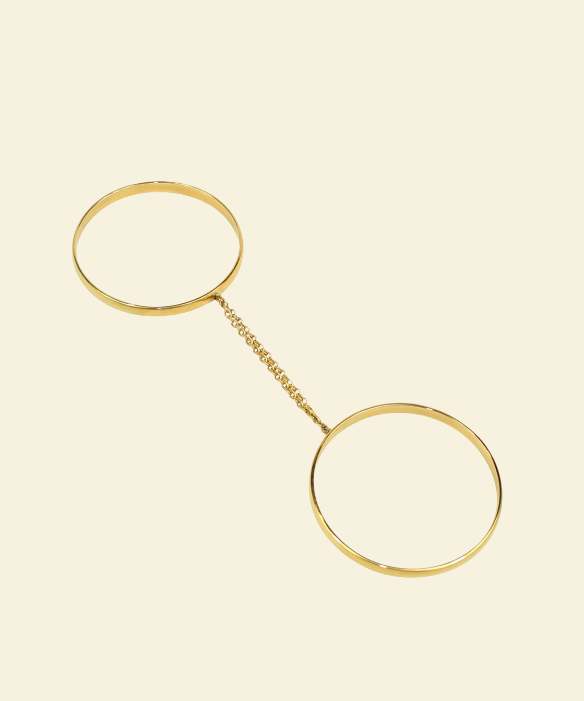 Gold bracelet with two circular ends on a beige background