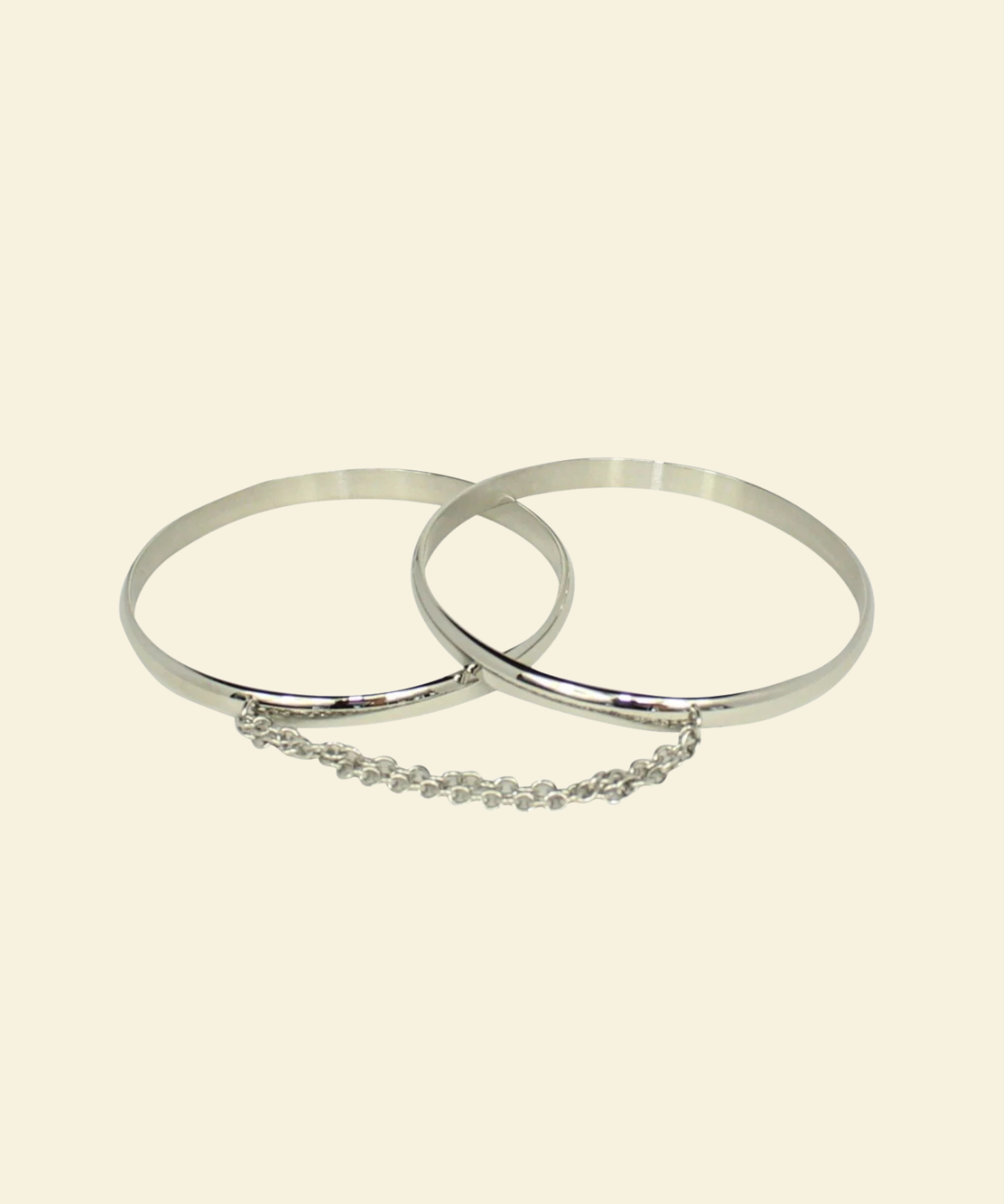 Two silver bangles with a chain on a beige background