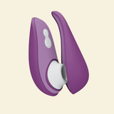 Purple Womanizer Air suction toy on beige background with it's travel case