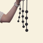 A hand holding 3 black anal beads in varying sizes