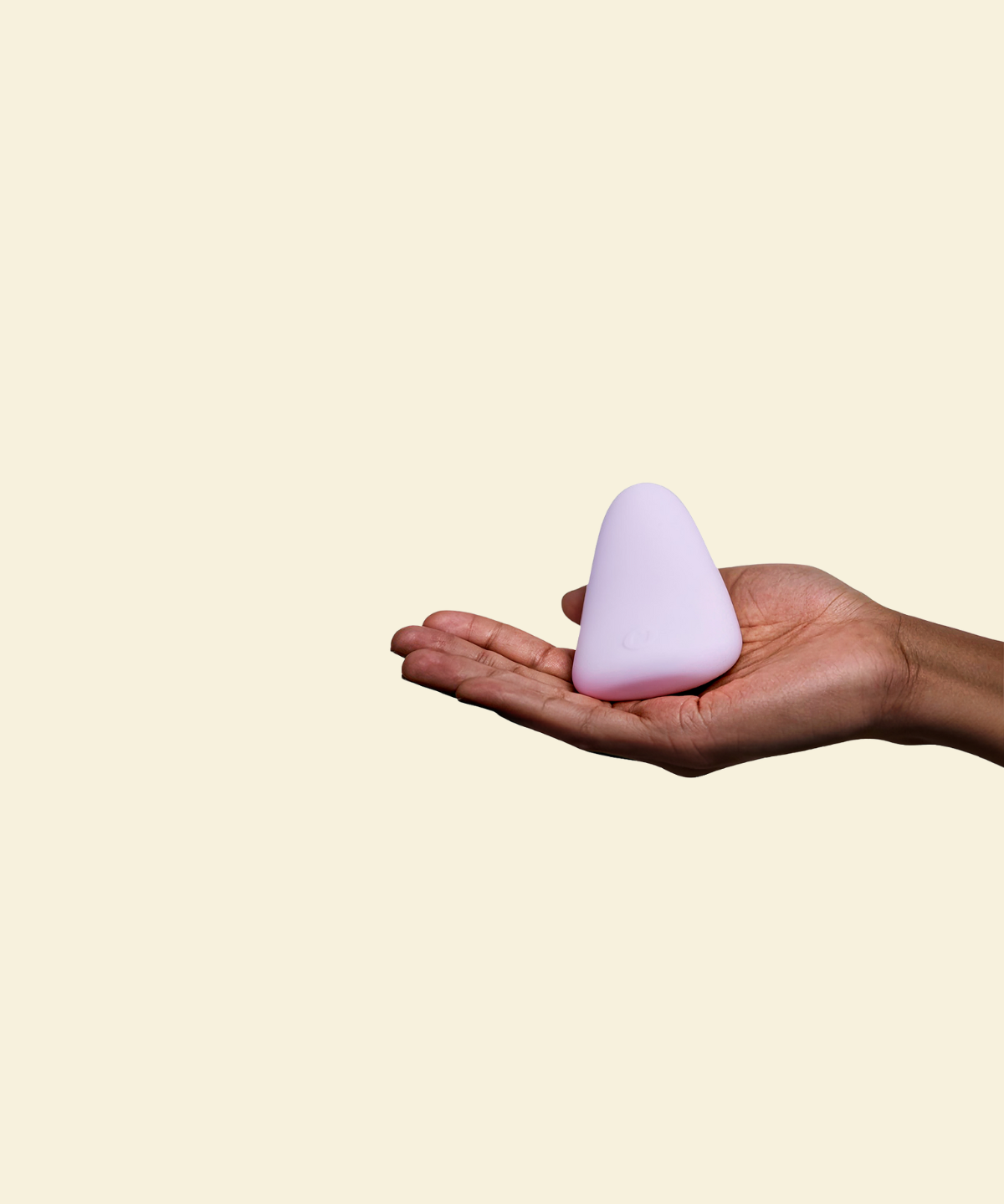 Purple silicone palm vibrator held in a hand on a beige back ground