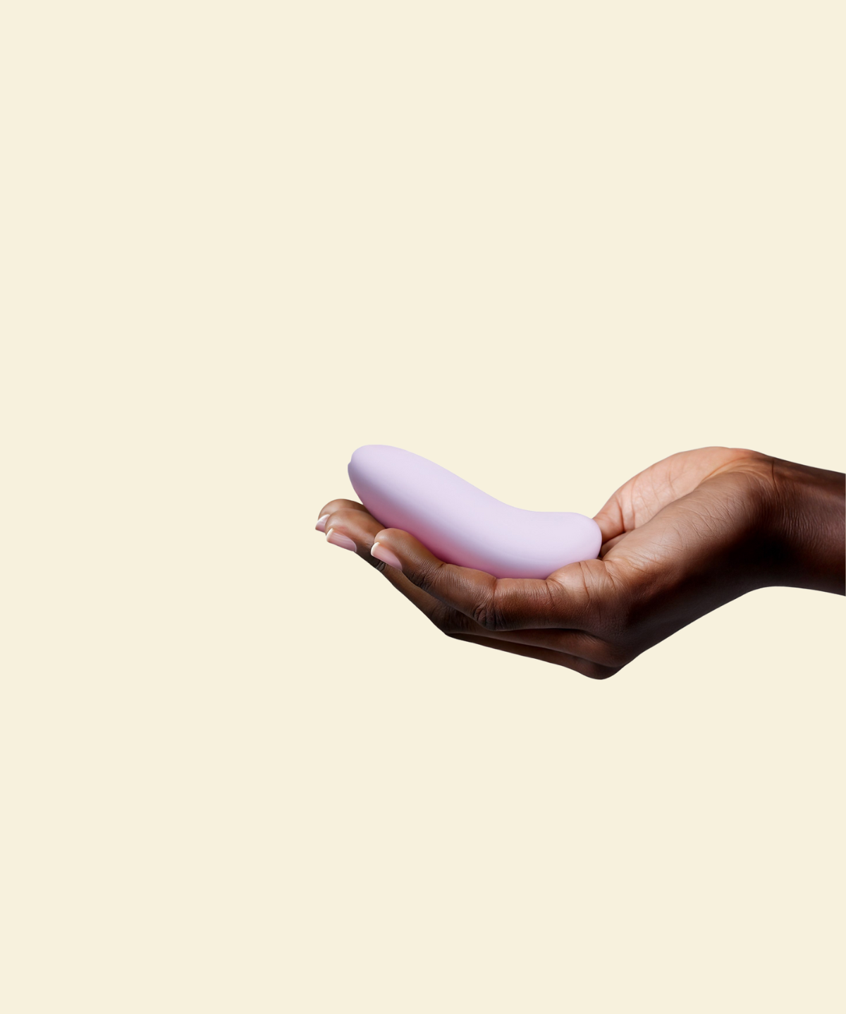 Hand holding a purple silicone palm vibrator on a beige background