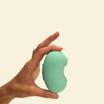 A hand holding a mint green air-suction toy