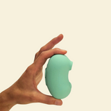 A hand holding a mint green air-suction toy