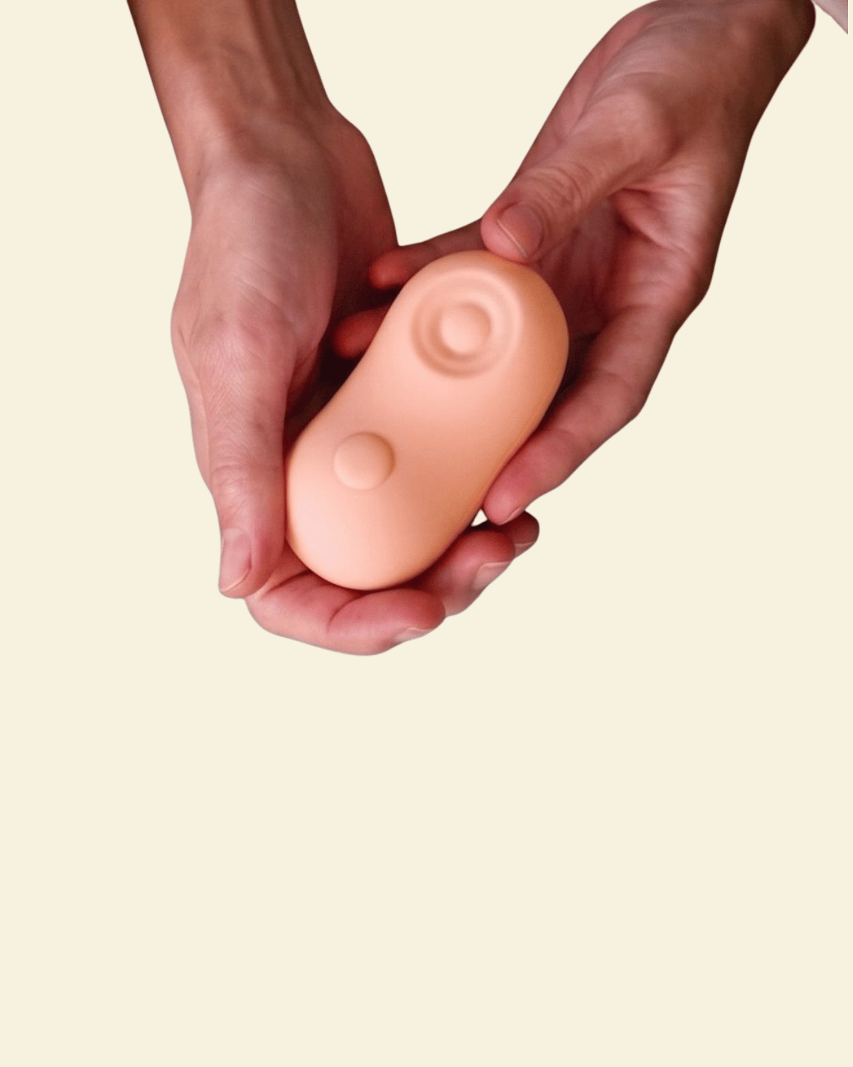 Two hands holding a coral colored tapping and vibrating massager 