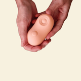 Two hands holding a coral colored tapping and vibrating massager 