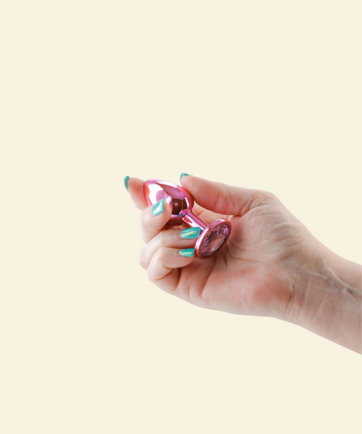 Hand holding a pink butt plug against a beige background