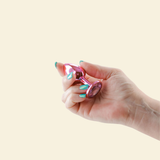 Hand holding a pink butt plug against a beige background