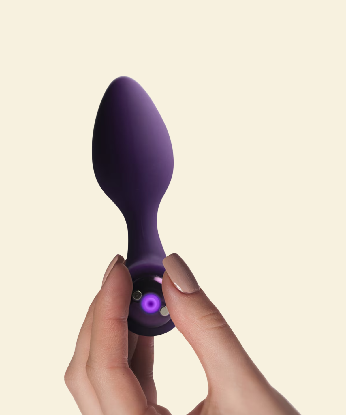 A hand holding a purple silicone vibrating butt plug
