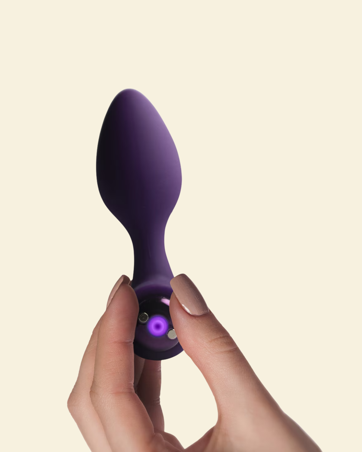 A hand holding a purple silicone vibrating butt plug