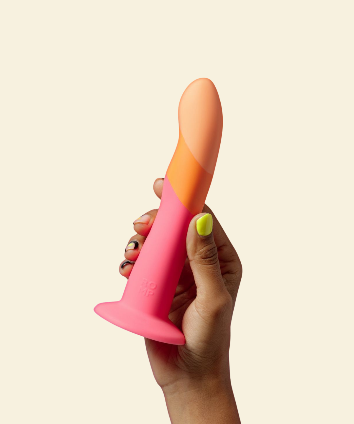 Hand holding a pink and orange dildo against a beige background