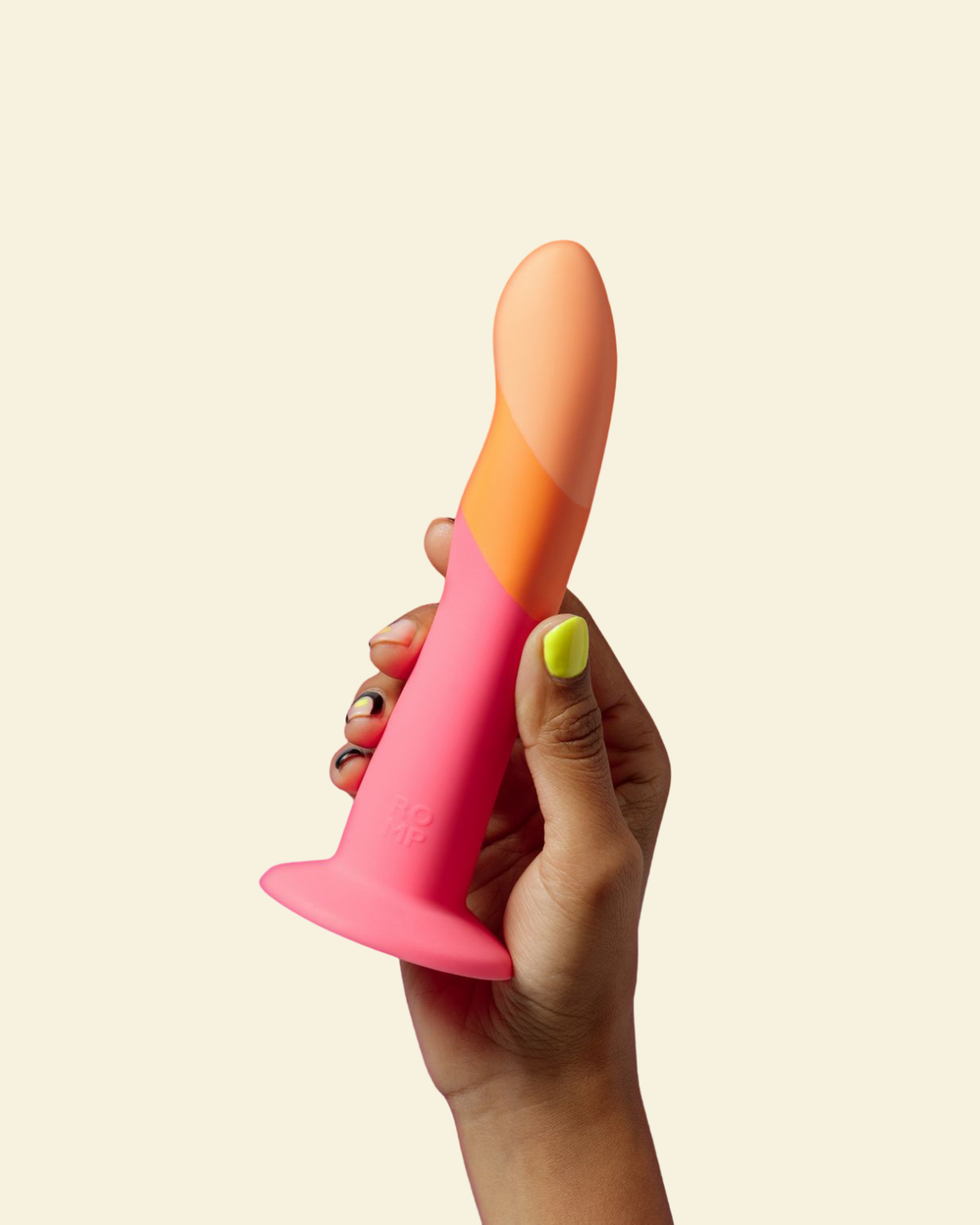 Hand holding a pink and orange dildo against a beige background