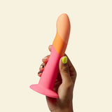 Hand holding a pink and orange dildo against a beige background