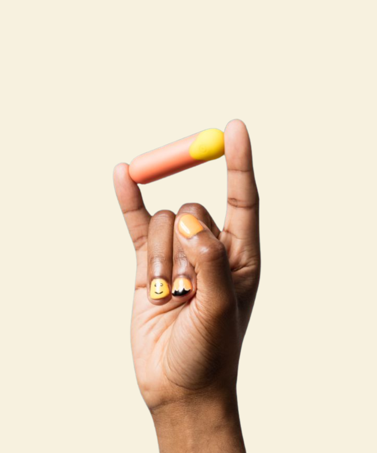 Hand with painted nails holding a red and yellow bullet vibrator between pinky and index finger