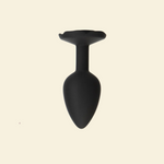 Black silicone butt plug on a beige background