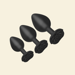 Set of black silicone butt plugs on a beige background