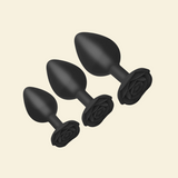 Set of black silicone butt plugs on a beige background