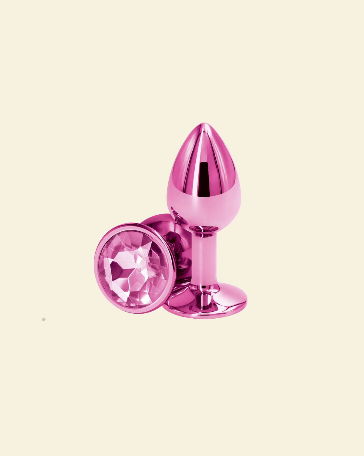 Pink metallic anal plug with a gemstone on a beige background