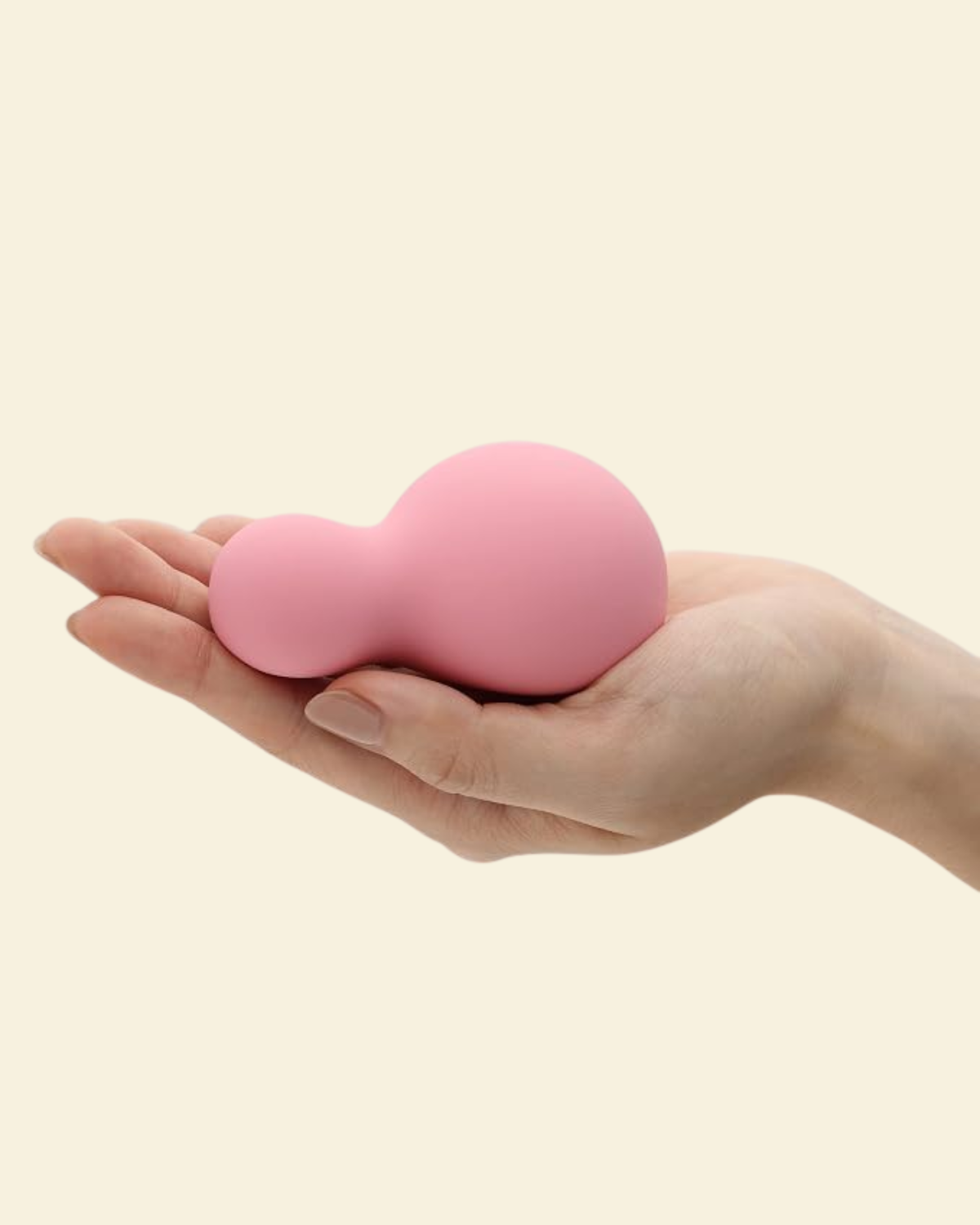 a Hand holding a small pink and soft silicone palm vibrator 