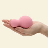 a Hand holding a small pink and soft silicone palm vibrator 