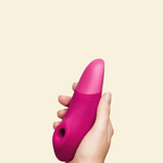Hand holding a pink Womanizer Enhance